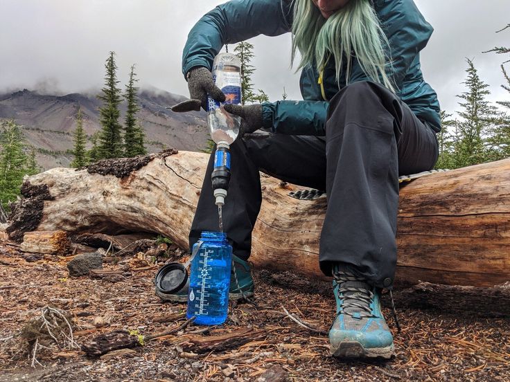 Female hiker filtering water on a trail in the Canadian Rockies
